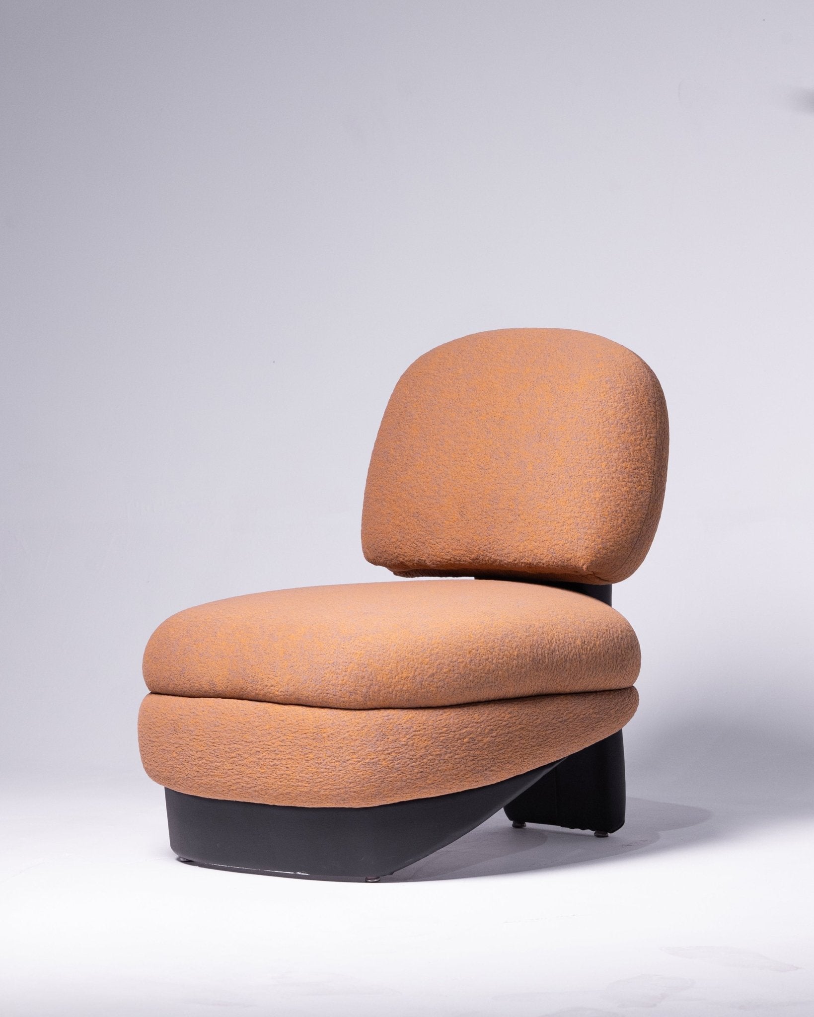 Modern sculptural lounge chair with terracotta fabric and a black base by Mahogni