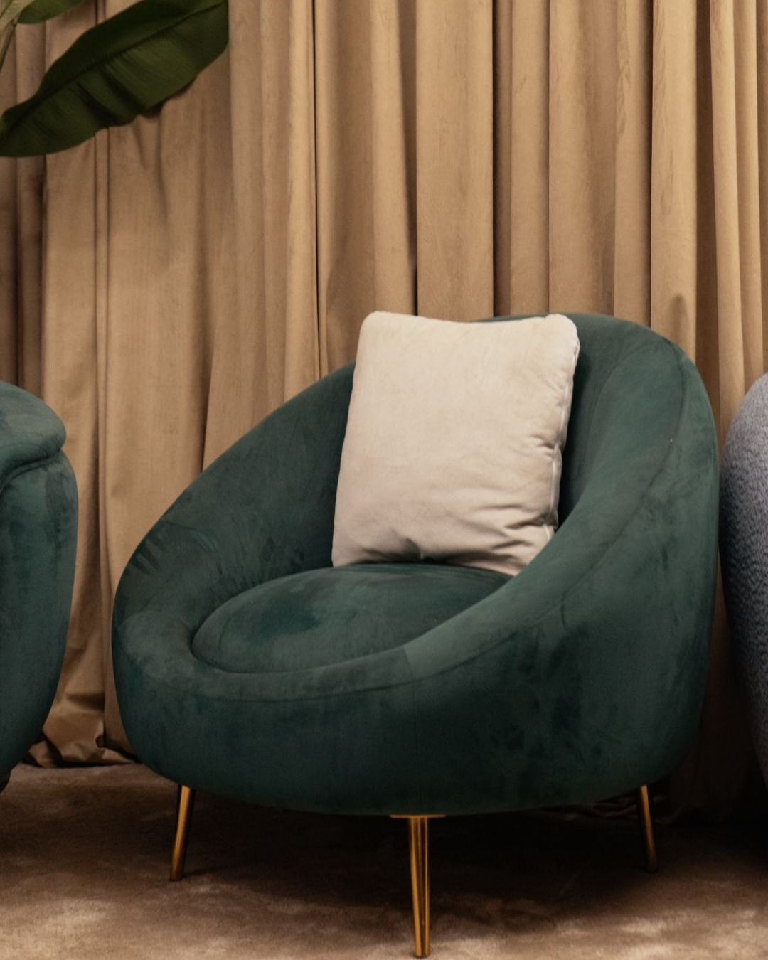 Luxury teal velvet round accent chair with gold metal legs and white pillow for modern home decor by Mahogni.