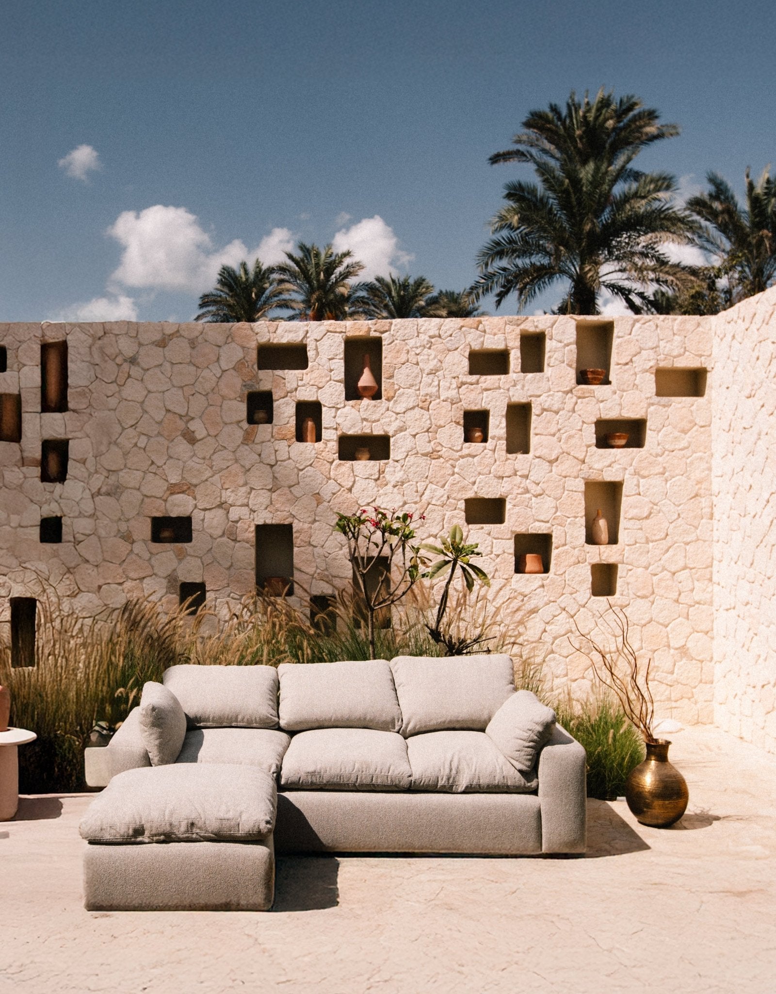 Modern L-shape outdoor/indoor sofa in a contemporary stone patio setting - Mahogni.