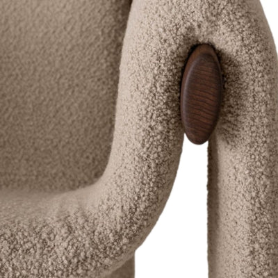 Close-up of a textured beige chair with a wooden armrest on a white background