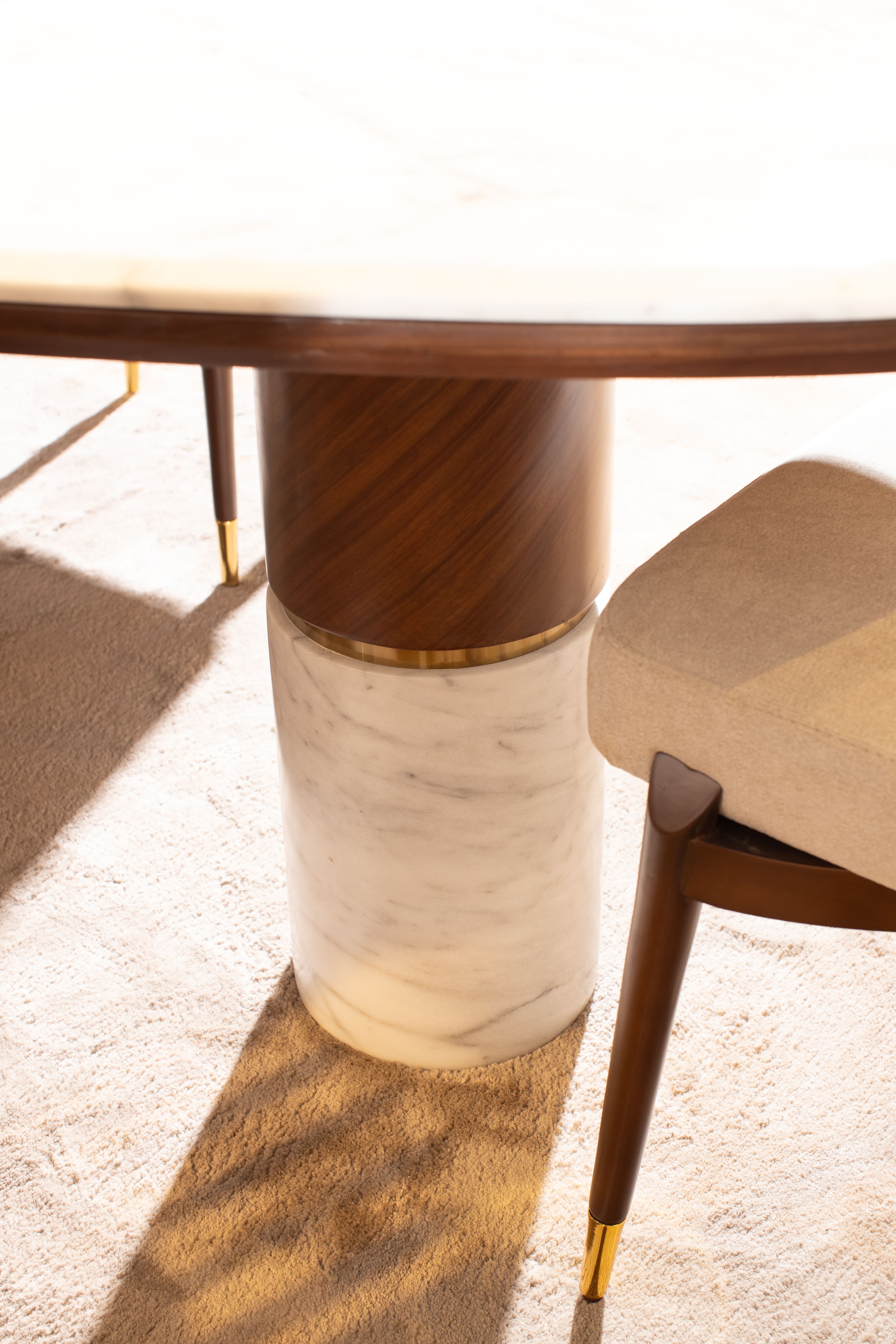 Detailed view of a Melt luxury dining table with beige fabric and walnut wood finish.