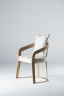 Elegant modern dining chair with a gold metal frame, cream textured upholstery, tan velvet armrests, and a matching back cushion against a white background.