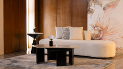 Extra-long modern curved sofa in white bouclé fabric, featuring a minimalist serpentine design and decorative geometric cushions, styled in an elegant room with a marble coffee table.