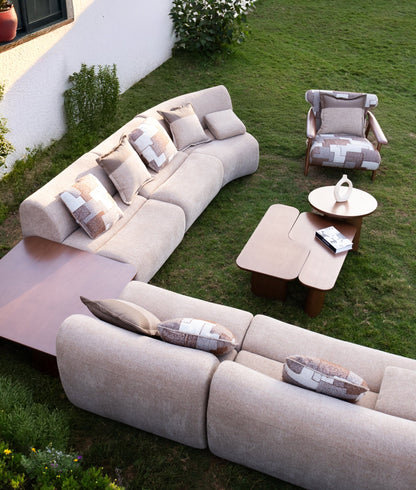 Soft living room set featuring a large modular sectional in warm beige textured fabric with geometric patterned cushions and dark wood coffee tables by Mahogni 