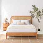 Solid oak wood bed frame with a natural woven cane rattan arched headboard in a bright minimalist bedroom by Mahogni.