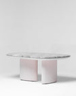 Contemporary oval dining table featuring a thick grey marble top and light pink textured pedestal base by Mahogni.