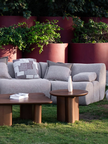 Soft living room set featuring a large modular sectional in warm beige textured fabric with geometric patterned cushions and dark wood coffee tables by Mahogni 