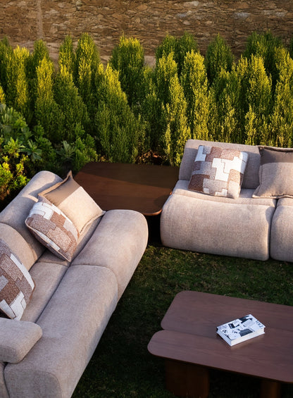 Soft living room set featuring a large modular sectional in warm beige textured fabric with geometric patterned cushions and dark wood coffee tables by Mahogni 