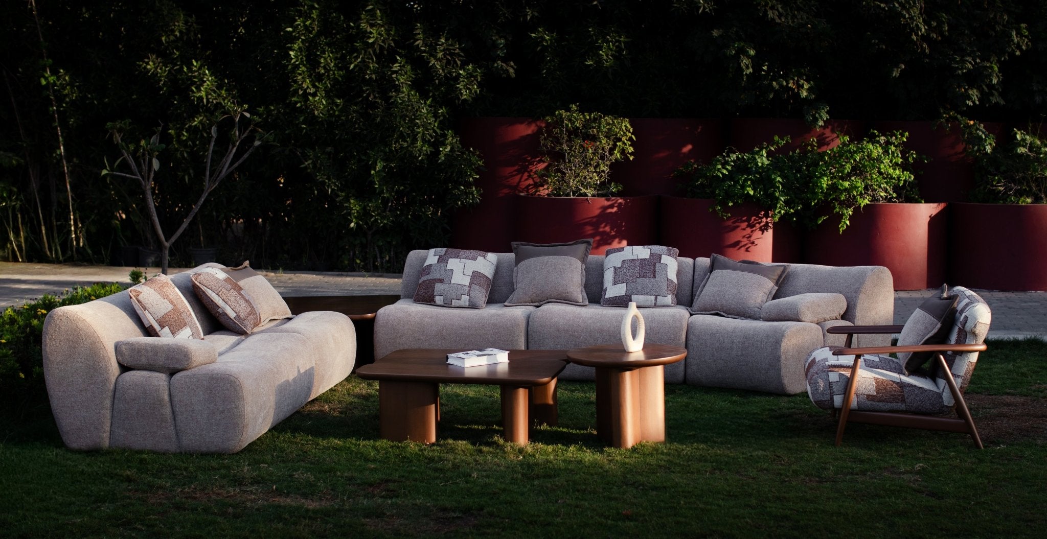 Soft living room set featuring a large modular sectional in warm beige textured fabric with geometric patterned cushions and dark wood coffee tables by Mahogni 