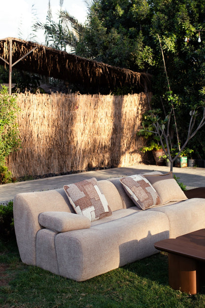 Soft living room set featuring a large modular sectional in warm beige textured fabric with geometric patterned cushions and dark wood coffee tables by Mahogni 