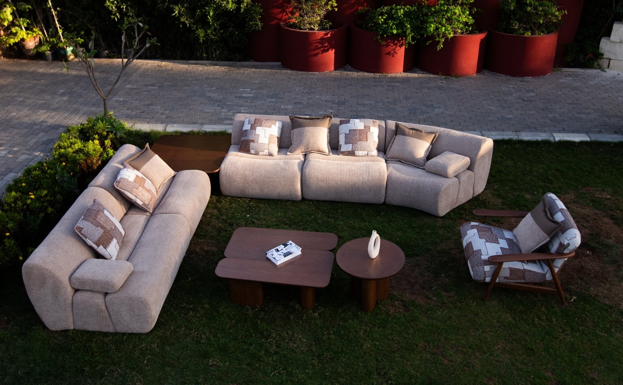 Soft living room set featuring a large modular sectional in warm beige textured fabric with geometric patterned cushions and dark wood coffee tables by Mahogni 