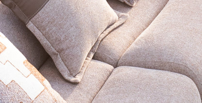 Soft living room set featuring a large modular sectional in warm beige textured fabric with geometric patterned cushions and dark wood coffee tables by Mahogni 