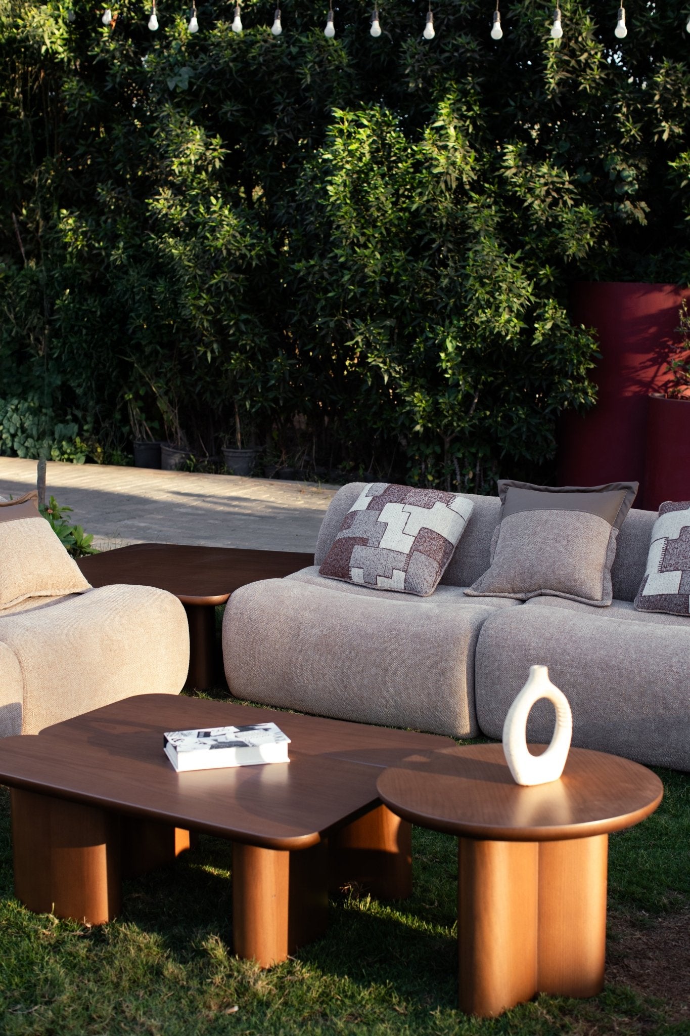 Soft living room set featuring a large modular sectional in warm beige textured fabric with geometric patterned cushions and dark wood coffee tables by Mahogni 
