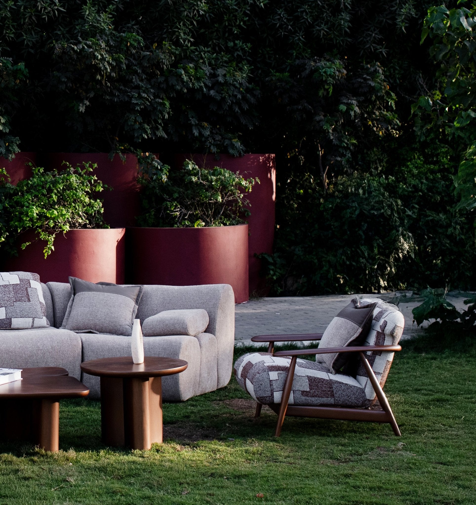 Soft living room set featuring a large modular sectional in warm beige textured fabric with geometric patterned cushions and dark wood coffee tables by Mahogni 